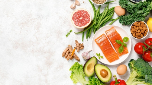 A colorful display of foods beneficial for managing menopause symptoms, including dairy products, whole grains, fruits like dark berries, vegetables, and omega-3-rich fish, set in a kitchen environment.